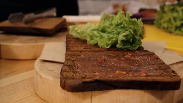 在厨房里做三明治 用酱汁贴上的油炸黑面包特写镜头 上面有一片绿叶的生菜 — 图库视频影像