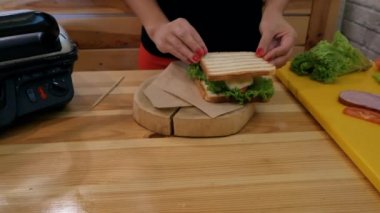 Bir kızın elini, taze domates, yeşil yaprak marul ve peynir sonra tahta bir sopa içine ekler ve daha yakın kamera için hamle mutfakta bir sandviçle Close-up