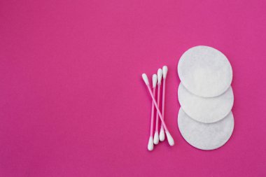 top view on pink cotton buds with white heads and white round cotton disks laid out on a pink background. clipart