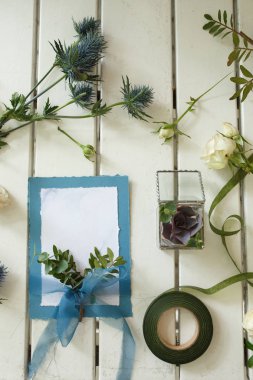 Taze beyaz gül ve beyaz ahşap masa üzerinde düğün davetiye kartı. Olay taze çiçek dekorasyon. Çiçekçi iş akışı. Düğün Ziyafet tasarım.