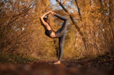 Genç kadın sarı yaprakları ile sonbahar park Yoga egzersiz pratik. Spor ve rekreasyon yaşam tarzı.