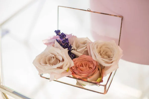 closeup glass box for wedding rings decorated with fresh rose flowers and banch of lavender. Event decoration with fresh flowers.