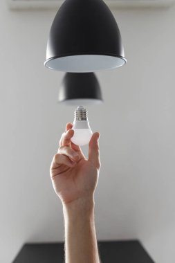 Lambanın ampulünü siyah lambayla değiştiriyorum. Açık gri arkaplanda.