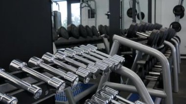 Spor salonunda dumbbells alarak seksi fitness kız. İnce, vücut geliştirmeci kız, asansörleri dumbbell ayakta ise eğitim ayna önünde spor salonunda