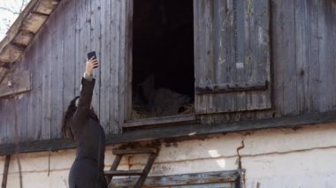 Genç bir kadın cep telefonu Evin çatısı Merdiven tırmanma ağı için arıyor. Uzak arazi, zavallı mobil iletişim