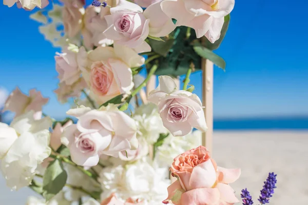 Parte do arco de casamento decorado com flores frescas está situado na margem arenosa do rio. florista casamento arranja fluxo de trabalho — Fotografia de Stock