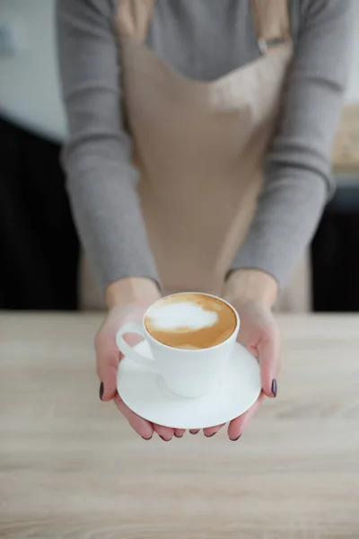 Barista in schort in coffeeshop geven alleen gebrouwen verse koffie naar klant — Stockfoto