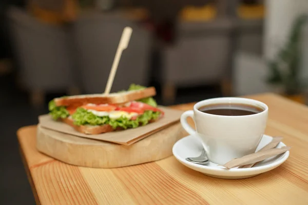 Frisches saftiges Sandwich mit heißem Kaffee auf Holztisch mit — Stockfoto