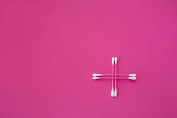 Top view on four pink cotton buds with white heads laid out in cross form  on a pink background — Stock Photo, Image