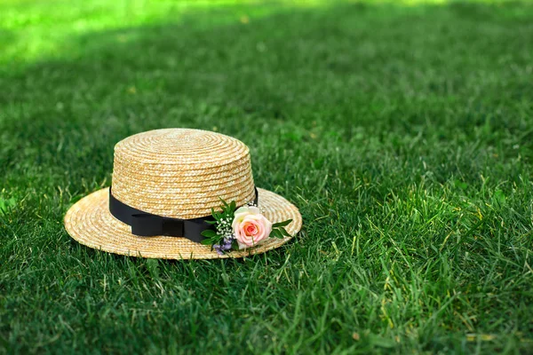 新鮮な花でスタイリッシュな麦わら帽子が緑の芝生の上に置く — ストック写真