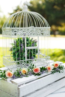 Festival rustik tarzı dekorasyon taze çiçekler ve bir ahşap kutu üzerinde beyaz kuş kafesi. Güneşli yaz gün