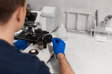 Laboratuar asistanı mikroskop arıyor. Araştırma laboratuarında olun. Bilim ve tıp kavramı