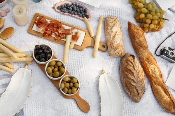Food lay out on picnic blanket. fresh baked bread, olives and photocam lay on white blanket. Picnic prepare decoration