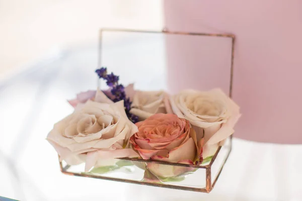 closeup glass box for wedding rings decorated with fresh rose flowers and banch of lavender. Event decoration with fresh flowers