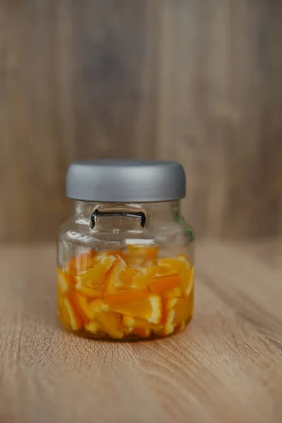 Mini botella de vidrio cerrado con fruta naranja en rodajas. Fondo de madera — Foto de Stock