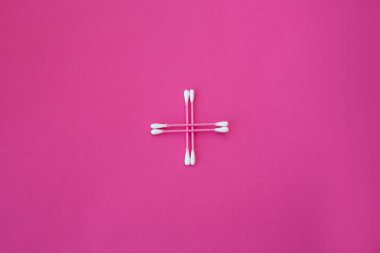 Pembe arka planda çapraz biçimli beyaz başlı dört pembe pamuk tomurcuğunun üst görüntüsü