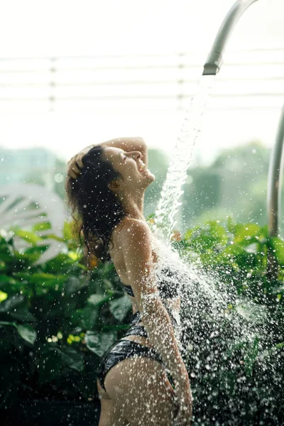 Sexy szczupła kobieta w stroju kąpielowym bierze prysznic w basen hotelowy parking. — Zdjęcie stockowe