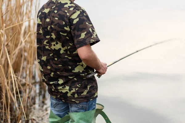 Pescador captura peces por el río. El hombre sostiene caña de pescar —  Fotos de Stock