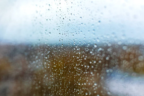 Gotas de chuva no vidro contra o pano de fundo da cidade de outono — Fotografia de Stock