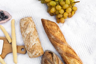 Piknik battaniye var yemek hazırlamak. taze pişmiş ekmek, üzüm, zeytin ve photocam beyaz battaniye var yatıyordu. Piknik hazırlamak dekorasyon