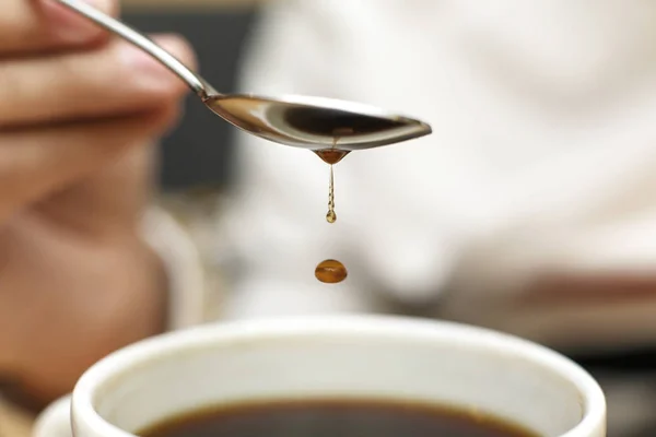 Close up blob of coffee dripping from metal spoon into mug with c — стоковое фото