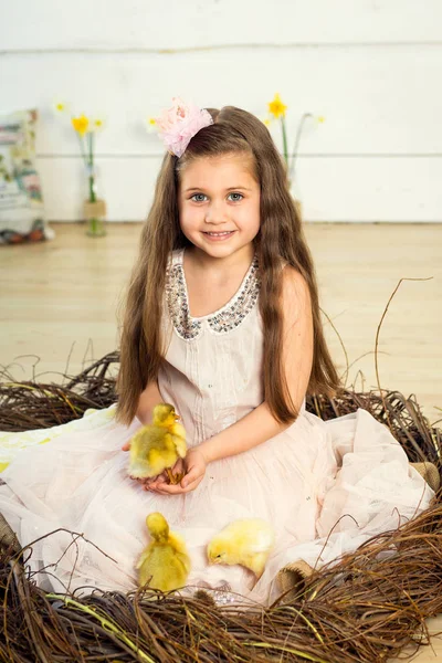 Elbiseli küçük kız mutlu bir yuvada oturur ve şirin kabartmak tutar — Stok fotoğraf