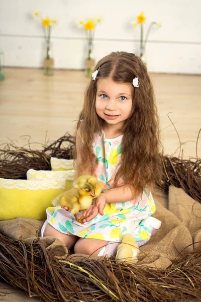 Elbiseli küçük kız mutlu bir yuvada oturur ve şirin kabartmak tutar — Stok fotoğraf