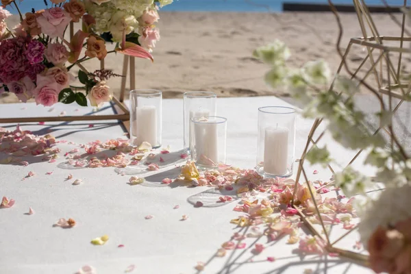 Fresh flower petals lie on the floor next to a decorated wedding arch and white candles. Event decoration with fresh flowers — Stock Photo, Image