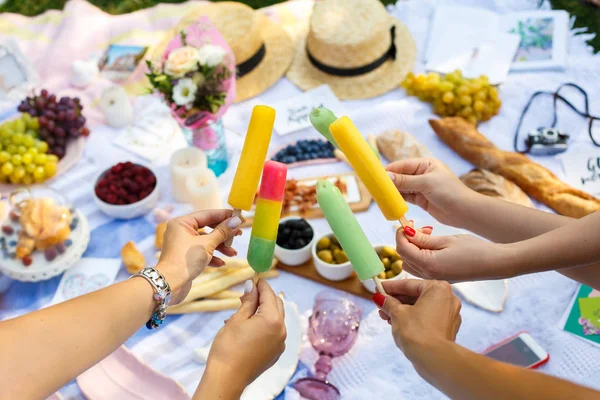 Woman hands hold colorful ice-cream sticks at summer picnic background. Summer weekends — Stock Photo, Image