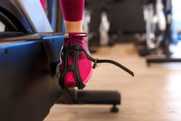 Closeup female leg in pedal of exercise bike