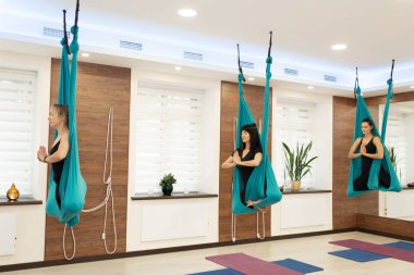 Women meditation in hammock. fly yoga stretching exercises in gym. Fit and wellness lifestyle