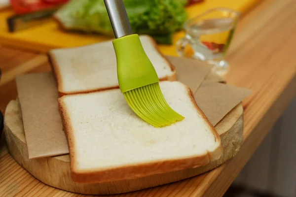 Espalhar o pão de óleo antes de fritá-lo na grelha — Fotografia de Stock