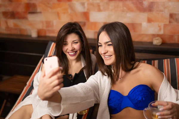 Dos chicas sexy hacen selfie en el teléfono mientras se relaja en Lou de madera —  Fotos de Stock