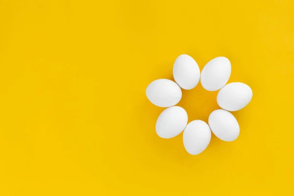 White chicken eggs lie in the form of a flower on a yellow background. Healthy organic food and diet concept. Abstraction. Easter theme Stock Picture
