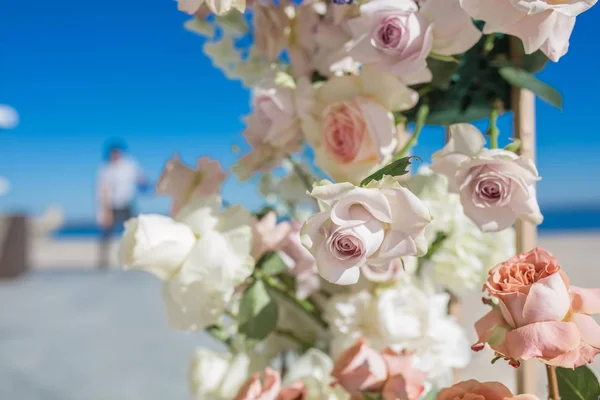 Onderdeel van de huwelijksboog gedecoreerd met verse bloemen ligt aan de zandige oevers van de rivier. Bruiloft bloemist regelt werkstroom — Stockfoto