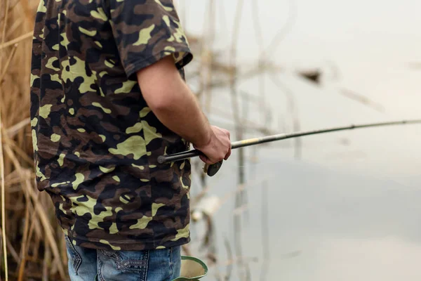 Рибалка ловить рибу біля річки. Чоловік тримає рибальський полюс — стокове фото