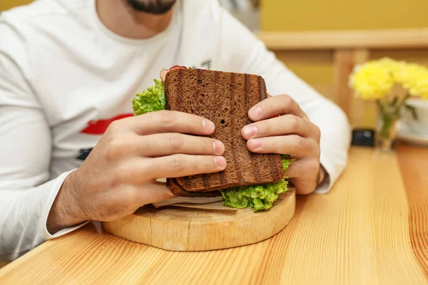 Jovem faminto em resaurante comer sanduíche — Fotografia de Stock