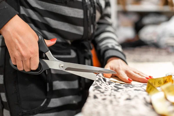 A young girl designer of clothes, cut fabric by pattern to create clothes in his workshop