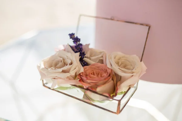 closeup glass box for wedding rings decorated with fresh rose fl