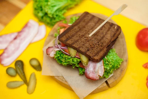 Σάντουιτς ψημένο σκούρο ψωμί στο ξύλινο πιάτο στο κίτρινο πλοίο — Φωτογραφία Αρχείου