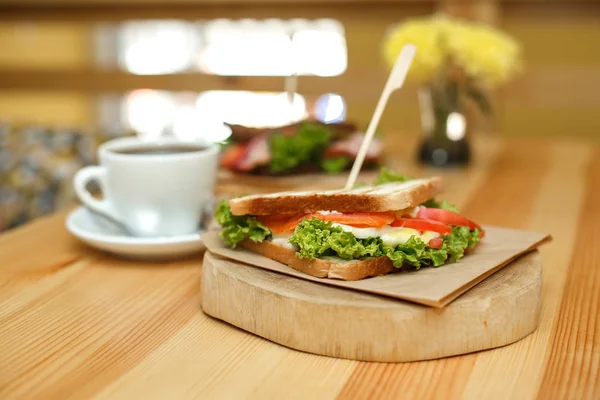 Fresh juicy sandwich with cup of hot coffee on wooden table with — Stock Photo, Image