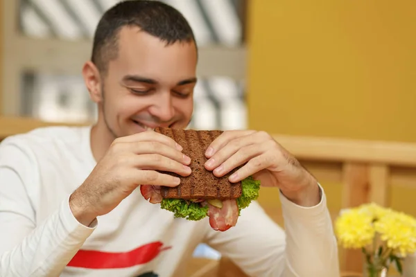 Hungry young man in resaurant eat sandwich