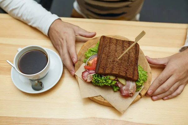 Чоловік в кафе бере бутерброд і каву на замовлення — стокове фото