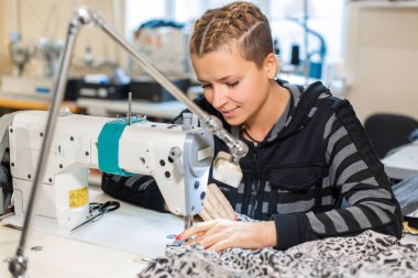 Dikiş terzisi makinede dikiş, portre. Kadın terzi dikiş malzemesi işyerinde. Giysi yapımı için kumaş hazırlama. Terzilik, konfeksiyon endüstrisi, tasarımcı atölye konsepti