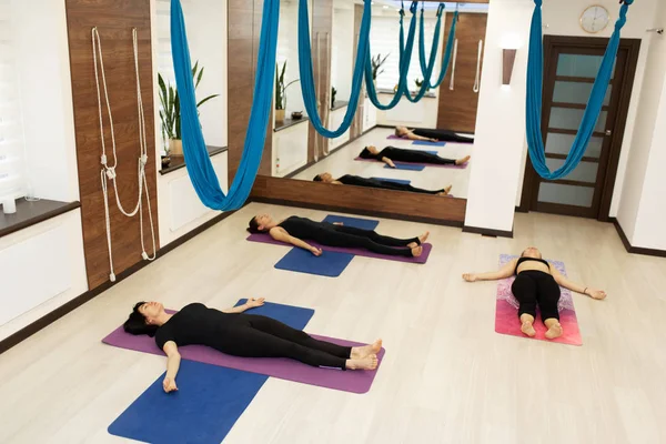 Vrouwen ontspannen op de vloer na het vliegen yoga oefeningen uit te rekken in de sportschool. — Stockfoto