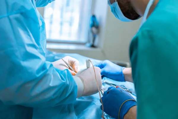 Mužský chirurg v masce a plášti působí ve sterilním provozuschopný — Stock fotografie