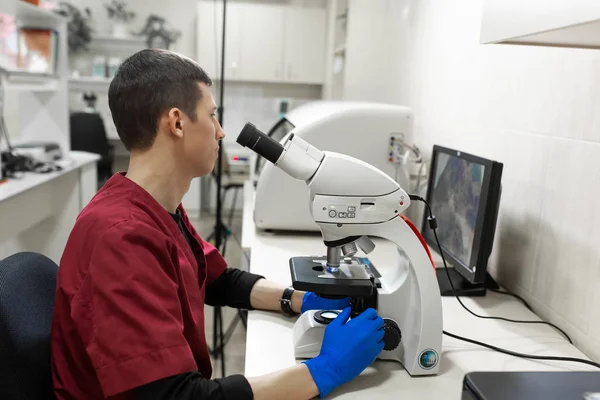 ドネプル/ウクライナ - 02.07.2019: 研究室で顕微鏡を通して見る若い科学者.若い科学者が研究を行う — ストック写真
