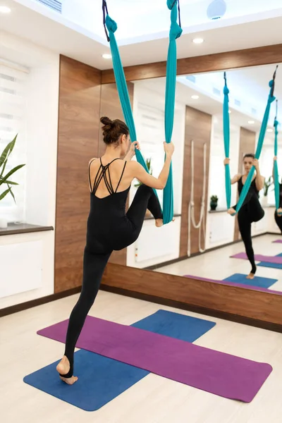 Wanita berdiri di tempat tidur gantung untuk latihan yoga terbang. Wanita melakukan latihan terbang yoga peregangan di gym. Fit and wellness gaya hidup — Stok Foto