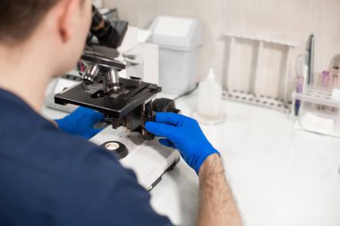 Laboratuvar asistanı mikroskoptan bakıyor. Araştırma yap i