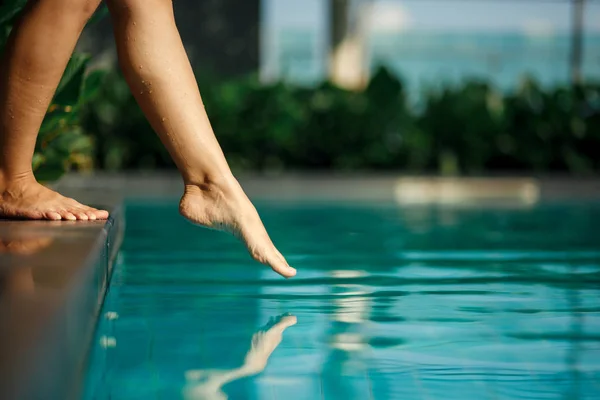 Closeup jovem fêmea perna toque água azul na piscina — Fotografia de Stock